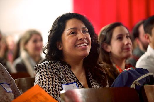 A smiling young woman watches a presentation in her North Carolina teacher prep program