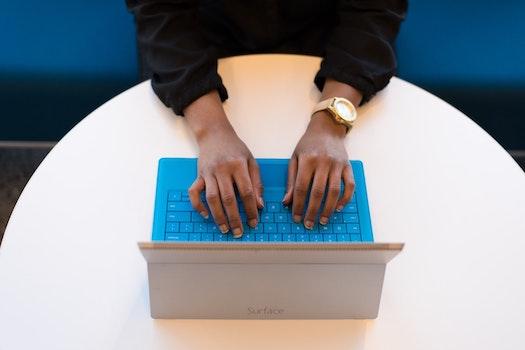 A student's hands on a blue laptop keyboard as they type their application personal statement.