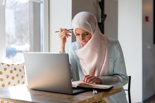 A Muslim woman sits at her laptop studying for her North Carolina content teaching exam.