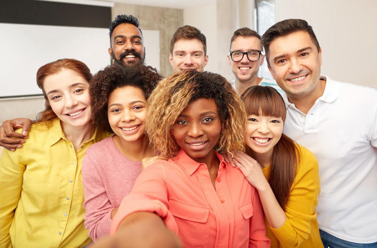 A group of eight diverse future North Carolina teachers gather for a group selfie. The person closest to the front holds out the camera in front of her to take the picture.